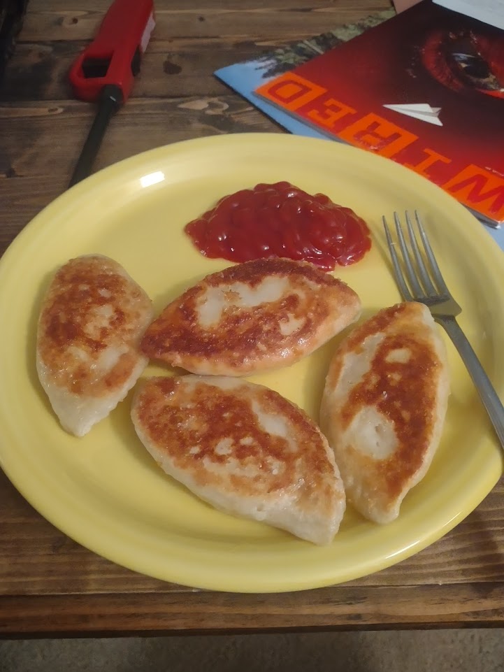 A plate of fried pierogis with ketchup.