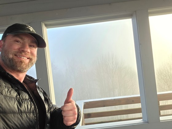 A man giving a thumb's up to a foggy view from the Rich Mountain Fire Tower.